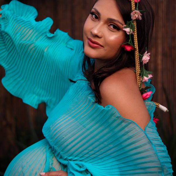 Portrait of a smiling woman in a serene outdoor setting with a turquoise border.