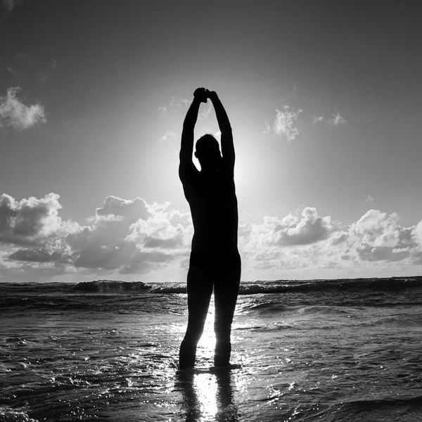 Silhouette of a person meditating at sunrise, symbolizing wellness and energy.
