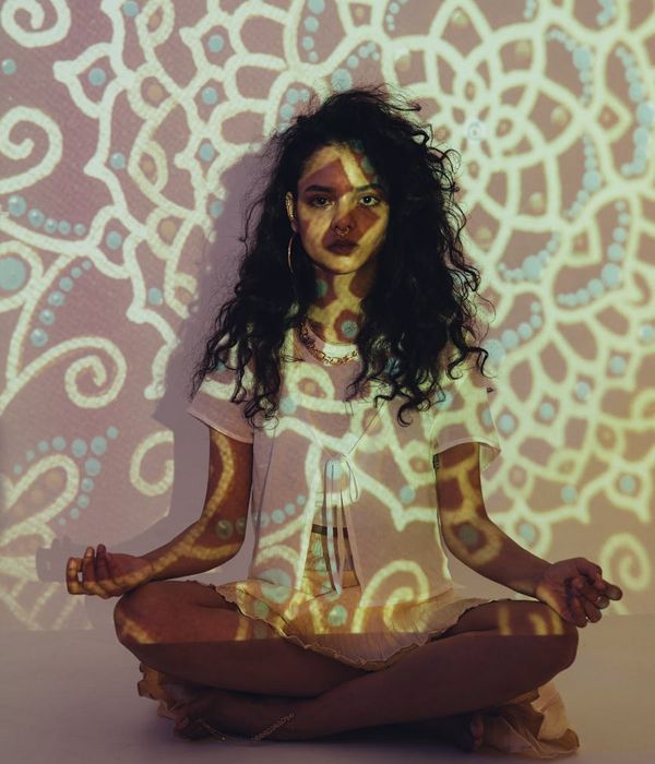 Woman in a calm yoga pose surrounded by abstract golden lines.